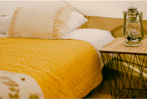 Yellow bed interior with lantern inside a furnished yurt